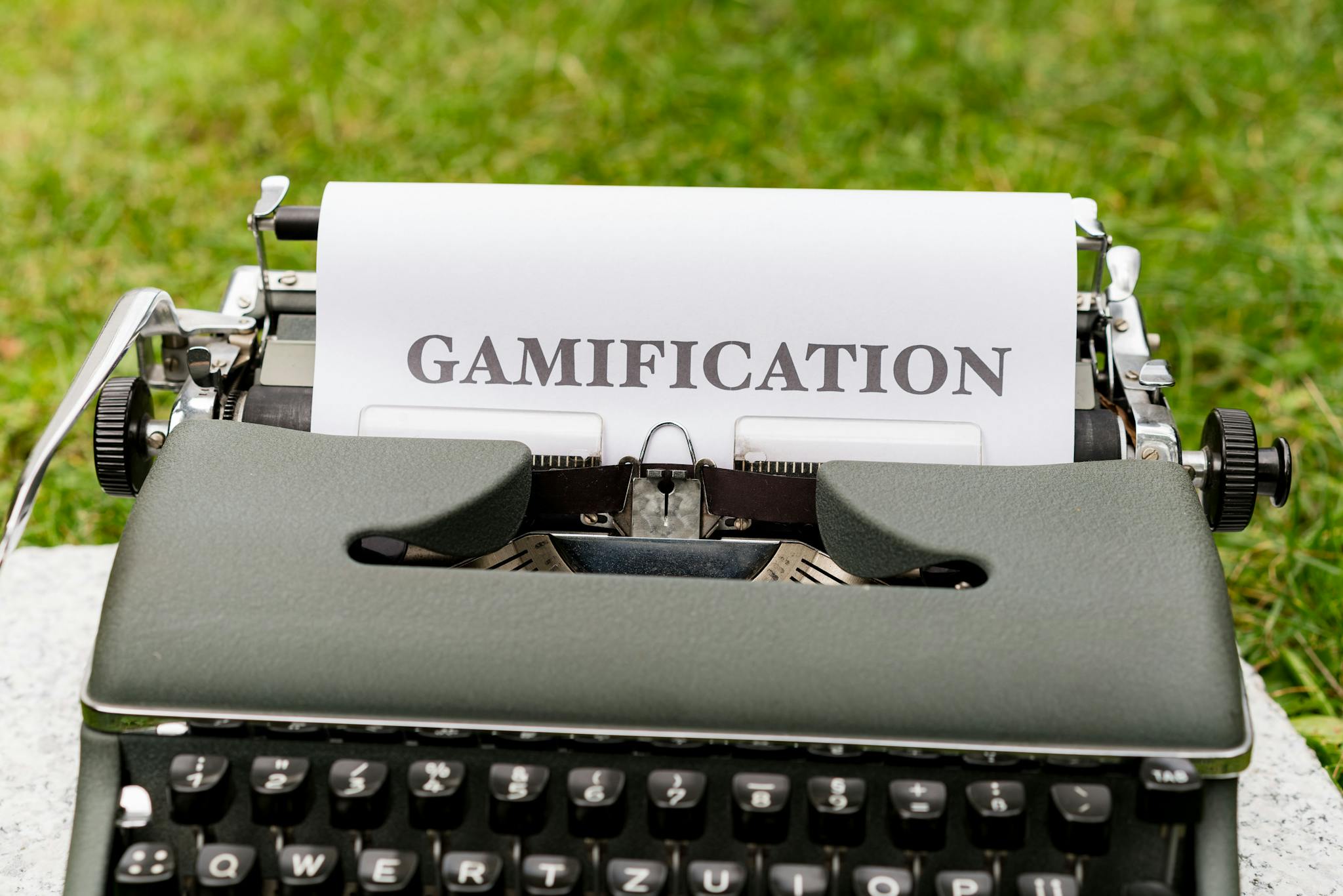 Close-up of a vintage typewriter displaying the word 'GAMIFICATION' on paper outdoors.